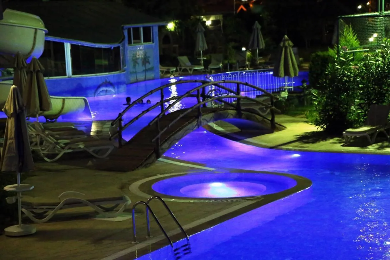 Beleuchteter Pool mit kleiner Brücke in einer Apartmentanlage in Mahmutlar am Abend