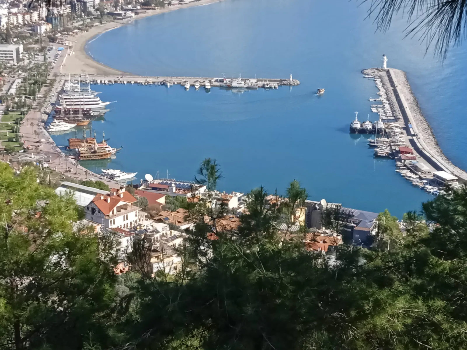 Hafen von Alanya mit Leuchtturm vom Burgberg aus gesehen, Sonne und blaues Wasser am 26. Dezember 2023